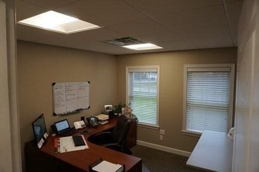 office area with a paneled ceiling, visible vents, and baseboards