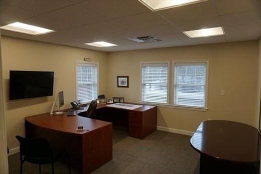 office space with a paneled ceiling, baseboards, and a wealth of natural light