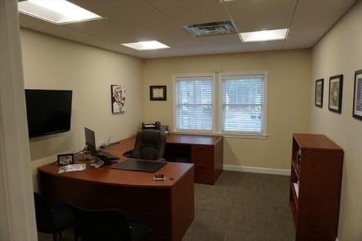 office area with carpet, baseboards, visible vents, and a drop ceiling