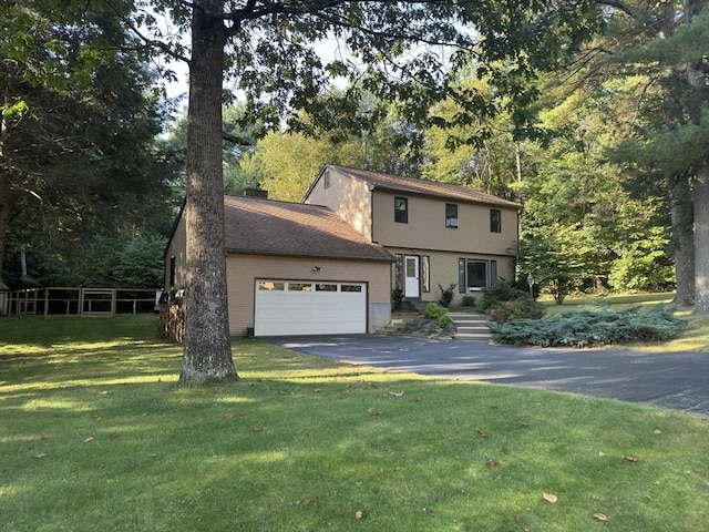 colonial-style house with driveway, a front lawn, a chimney, and an attached garage