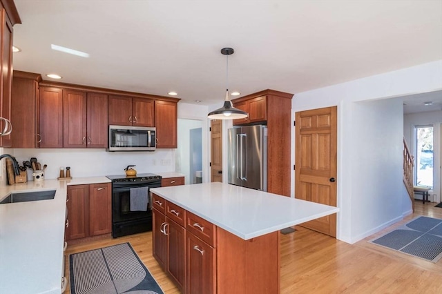 kitchen featuring appliances with stainless steel finishes, light wood-type flooring, light countertops, and a sink