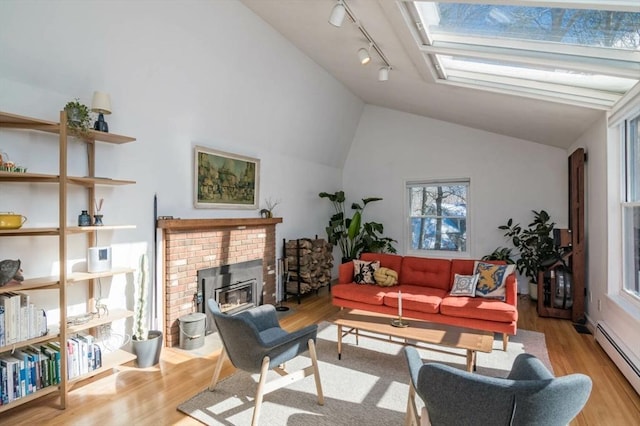 living room featuring a baseboard radiator, a brick fireplace, a skylight, and wood finished floors