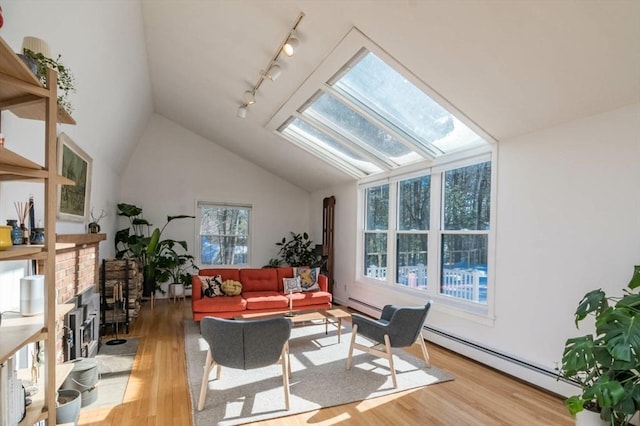 living room featuring a baseboard heating unit, vaulted ceiling with skylight, and light wood finished floors