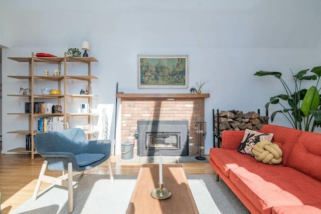 living room with a brick fireplace and wood finished floors