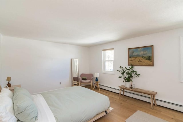 bedroom featuring a baseboard heating unit and light wood-style flooring