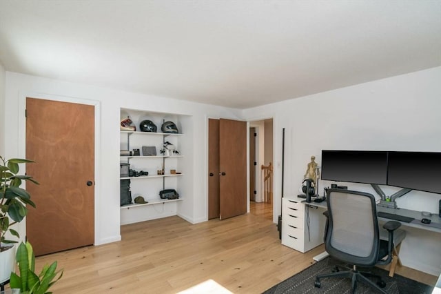 office with light wood-style flooring and built in features