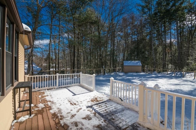 snow covered deck featuring an outbuilding, fence, and a shed