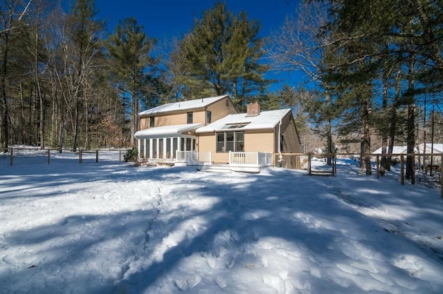 exterior space with a chimney, fence, and a sunroom