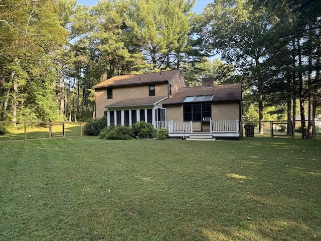 rear view of house featuring a yard, a sunroom, a gate, fence, and a deck