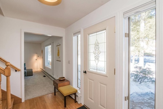 entryway featuring light wood-style floors, a wealth of natural light, stairway, and a baseboard radiator