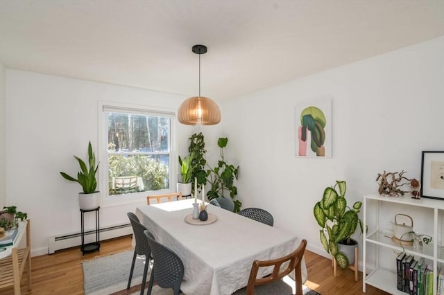 dining space with a baseboard radiator, wood finished floors, and baseboards