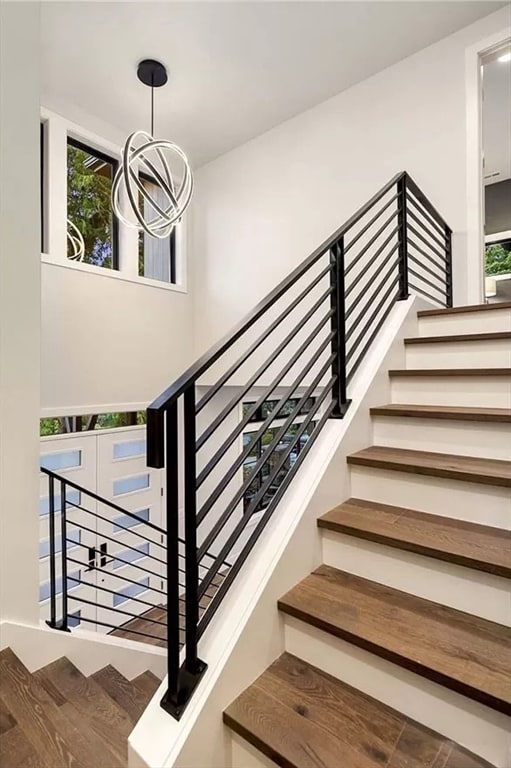 stairway with hardwood / wood-style floors and a notable chandelier