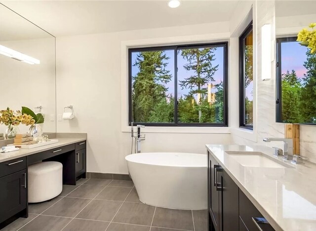 bathroom with tile patterned floors, a tub, and vanity