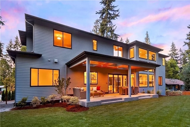 back house at dusk with a yard and outdoor lounge area