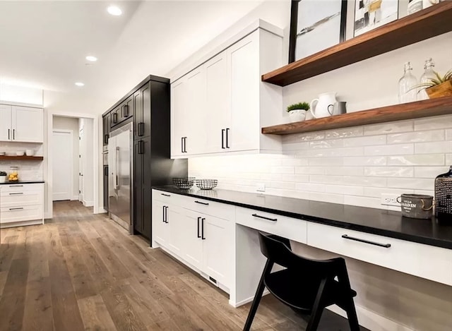 kitchen with white cabinetry, light hardwood / wood-style flooring, backsplash, and stainless steel built in fridge