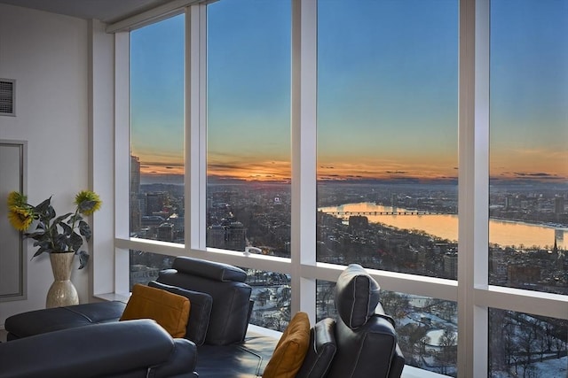 sunroom featuring a view of city, a water view, and visible vents