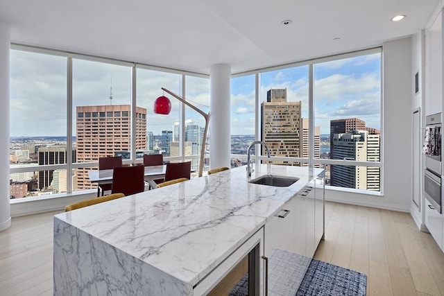 kitchen with a view of city, white cabinets, a sink, and a center island with sink