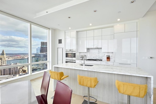 kitchen with stainless steel double oven, white cabinets, backsplash, and a city view