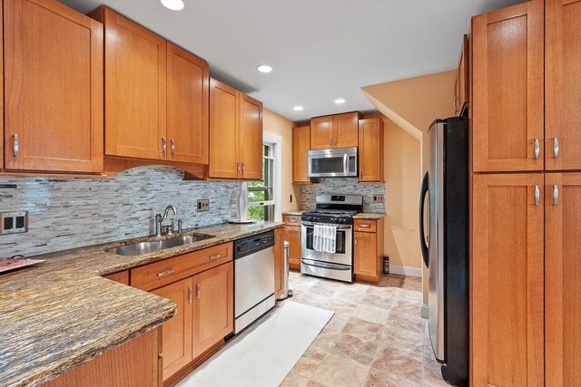 20 Walden St, Lowell, MA 01851 - kitchen with stainless steel appliances, a sink, dark stone counters, backsplash, and brown cabinets