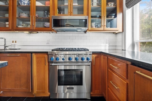 kitchen with dark stone counters, backsplash, stainless steel appliances, and sink