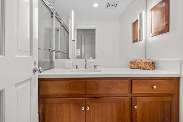 bathroom featuring ornamental molding, vanity, and a shower with shower door