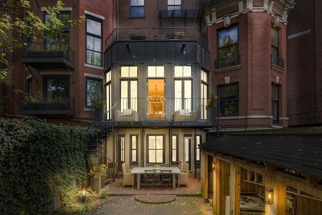 back of house with a balcony, an outdoor living space, and a patio area