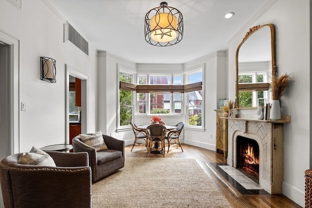 sitting room featuring plenty of natural light, ornamental molding, a premium fireplace, and hardwood / wood-style flooring