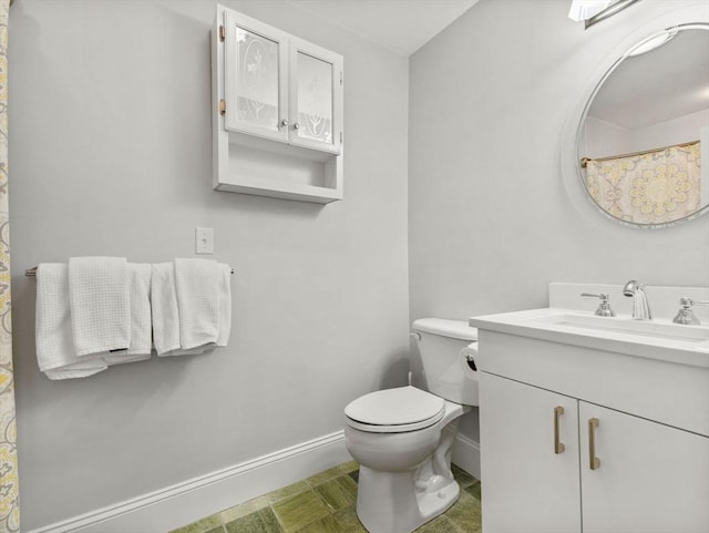 bathroom featuring vanity, toilet, and baseboards