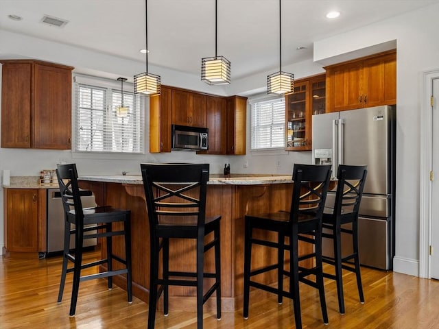 kitchen featuring light wood finished floors, visible vents, a healthy amount of sunlight, and stainless steel appliances