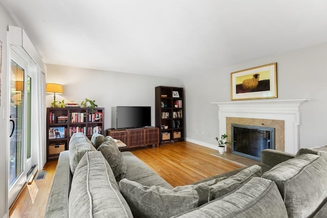 living area featuring visible vents, a glass covered fireplace, and wood finished floors