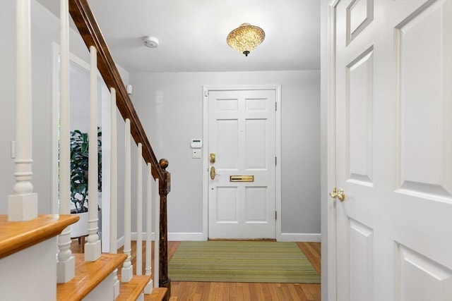 entryway with stairs, baseboards, and light wood finished floors