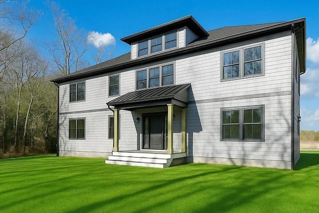 back of property featuring a standing seam roof, a lawn, and metal roof
