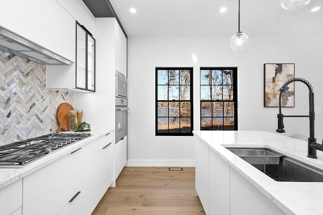 kitchen with a sink, white cabinets, light wood-style flooring, and recessed lighting