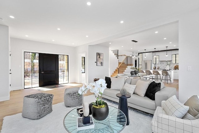 living room with stairs, recessed lighting, light wood-style flooring, baseboards, and a chandelier