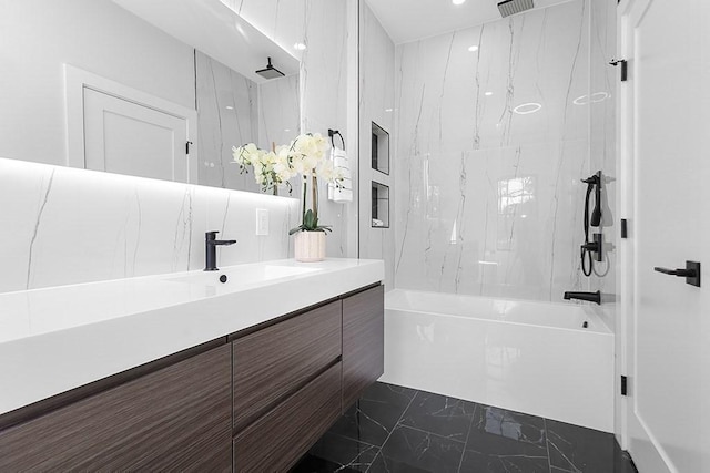 bathroom with marble look tiles, a combined bath / shower with rainfall shower, and vanity