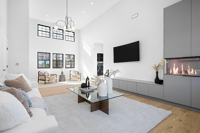 living area with a high ceiling, wood finished floors, a chandelier, and recessed lighting