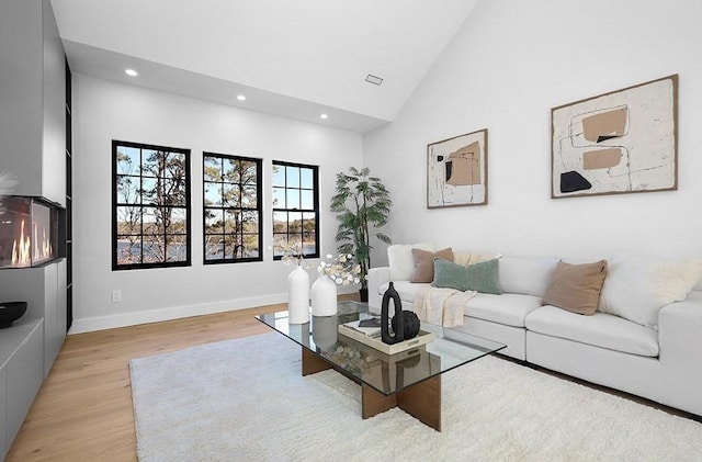 living area with light wood-style flooring, recessed lighting, high vaulted ceiling, and baseboards