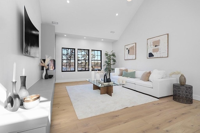 living area with high vaulted ceiling, light wood-type flooring, recessed lighting, and baseboards