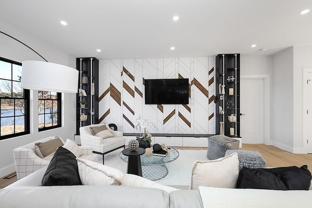 living room with baseboards, light wood finished floors, recessed lighting, and an accent wall
