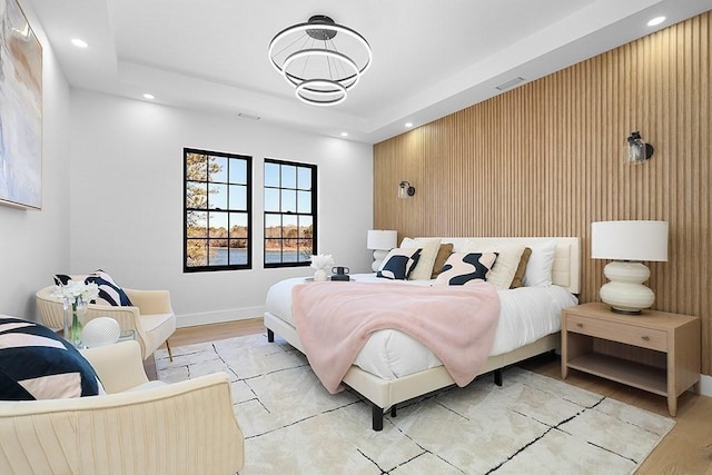 bedroom featuring light wood finished floors, recessed lighting, a raised ceiling, and baseboards