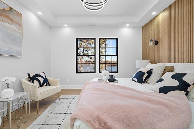 bedroom with wood finished floors, recessed lighting, baseboards, and a tray ceiling