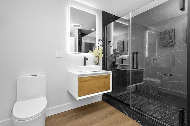 full bathroom featuring toilet, wood finished floors, a marble finish shower, and vanity