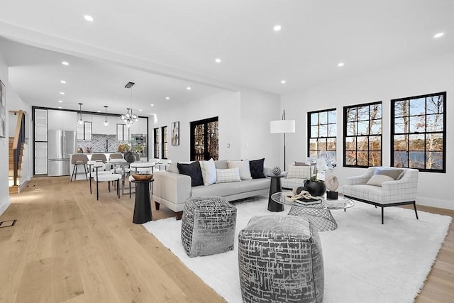living area with recessed lighting, light wood finished floors, baseboards, and beam ceiling