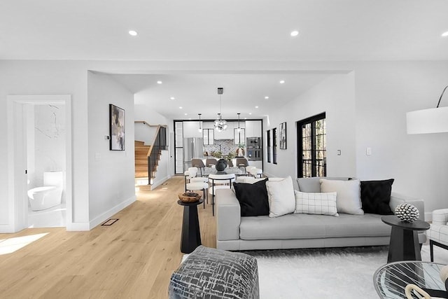 living area featuring stairway, light wood-style floors, recessed lighting, baseboards, and a chandelier