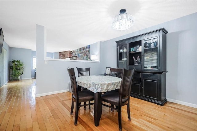 dining room featuring baseboards, an inviting chandelier, and light wood-style flooring