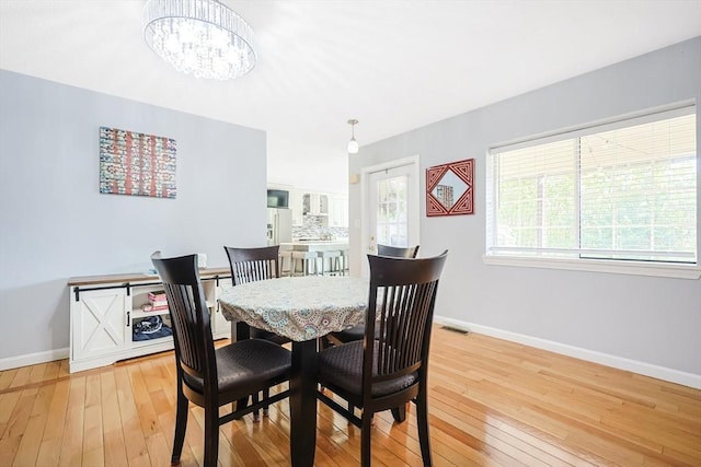 dining space featuring baseboards, an inviting chandelier, visible vents, and light wood-style flooring