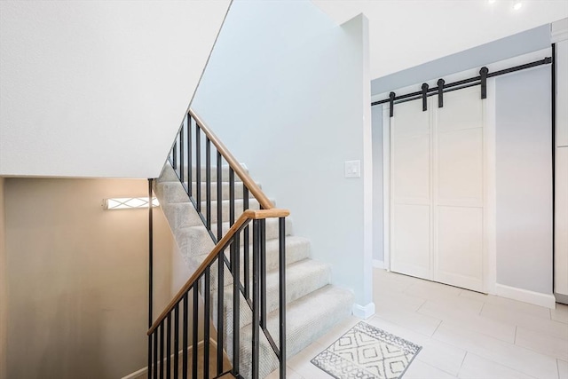 stairs featuring tile patterned floors, baseboards, and a barn door