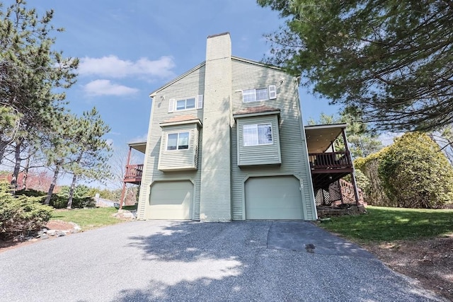 view of front facade with a chimney, a front lawn, driveway, and a garage