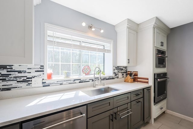 kitchen with decorative backsplash, gray cabinetry, stainless steel appliances, and a sink