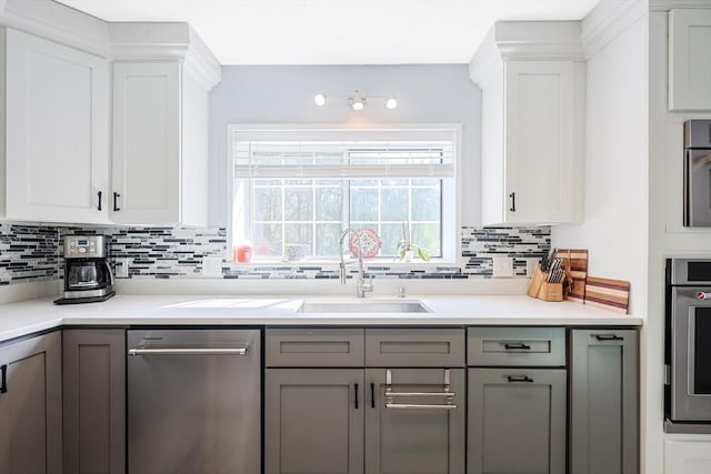 kitchen featuring gray cabinets, backsplash, appliances with stainless steel finishes, and a sink